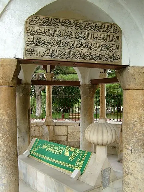 Akşehir Nasreddin Hoca Türbesi içinde yeşil örtülü sanduka, sütunlar ve giriş kitabesi